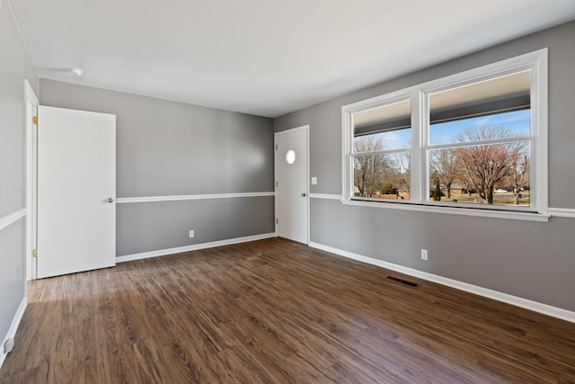 spare room with baseboards, visible vents, and wood finished floors