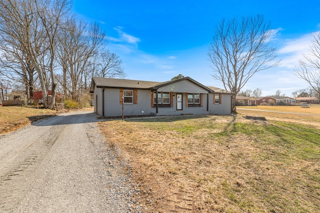 ranch-style home with gravel driveway, a front yard, and brick siding