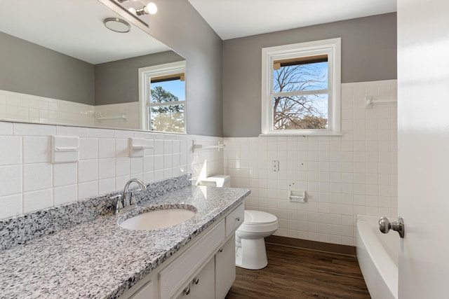 full bathroom featuring a wainscoted wall, tile walls, toilet, vanity, and wood finished floors