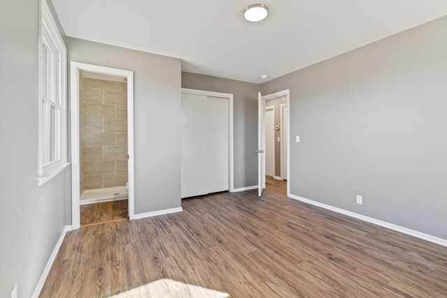 unfurnished bedroom featuring connected bathroom, a closet, baseboards, and wood finished floors