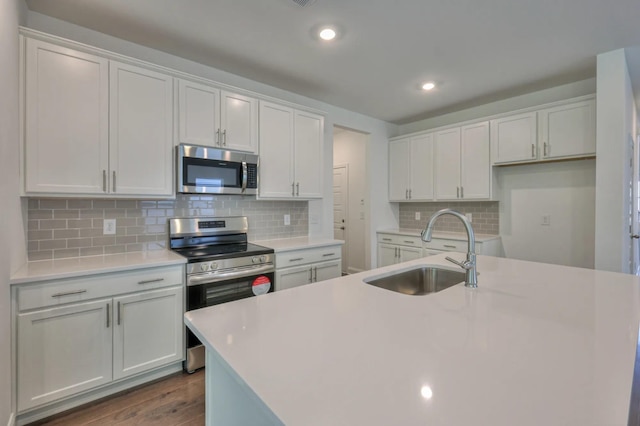 kitchen with white cabinets, dark wood-style flooring, stainless steel appliances, light countertops, and a sink