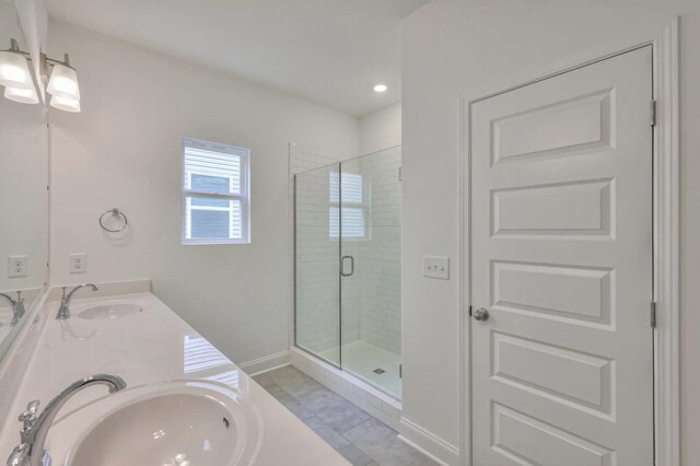 bathroom featuring double vanity, a stall shower, baseboards, and a sink