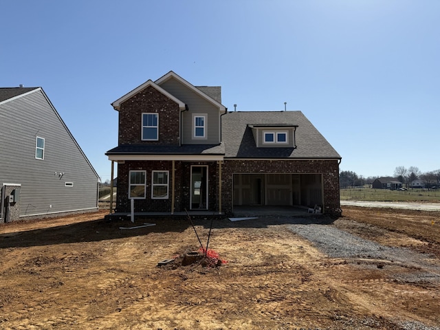 view of front of house featuring a garage, brick siding, a porch, and driveway