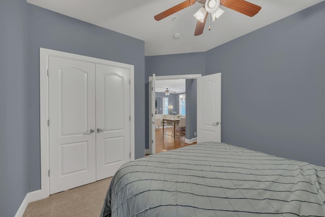 carpeted bedroom with a ceiling fan, a closet, and baseboards