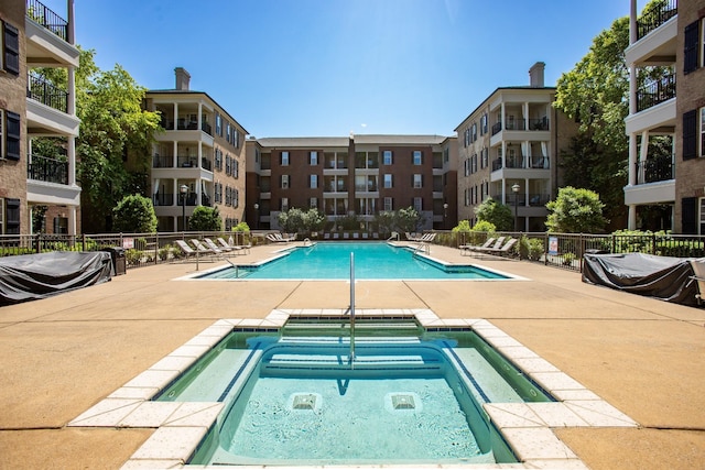 pool featuring a patio, fence, and a hot tub