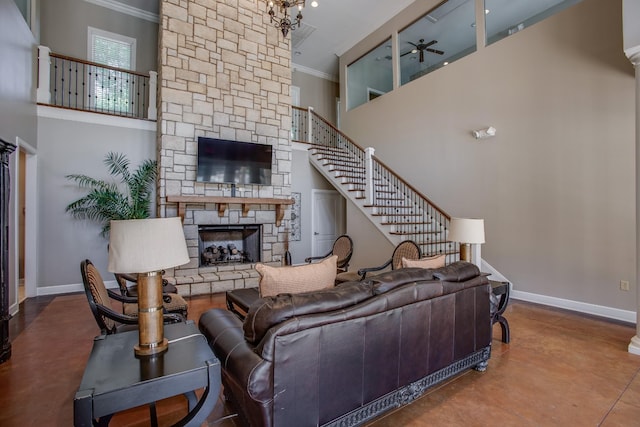 living room with baseboards, a high ceiling, ornamental molding, and a stone fireplace