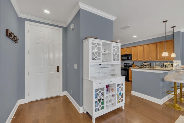 kitchen featuring a breakfast bar area, wood finished floors, ornamental molding, black appliances, and open shelves