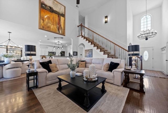 living area featuring arched walkways, hardwood / wood-style floors, a chandelier, baseboards, and stairs