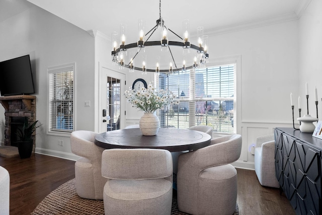 dining room with a wainscoted wall, crown molding, a fireplace, and dark wood-style flooring