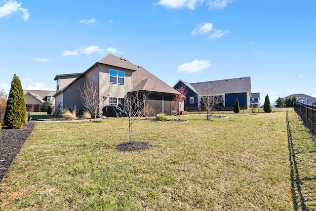 rear view of property featuring a sunroom, a fenced backyard, and a yard