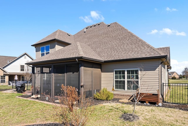 rear view of house with a sunroom, a shingled roof, fence, and a yard