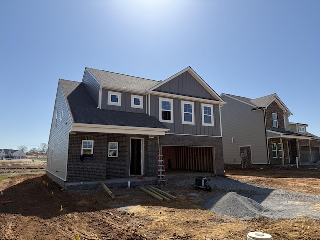 view of front of house featuring brick siding, driveway, a garage, and board and batten siding