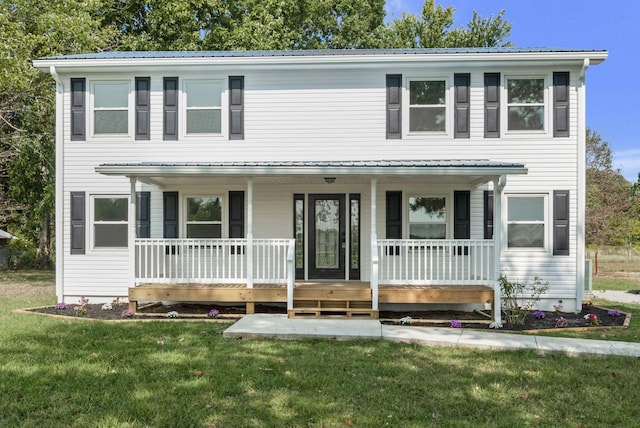 view of front of property featuring covered porch, metal roof, and a front yard