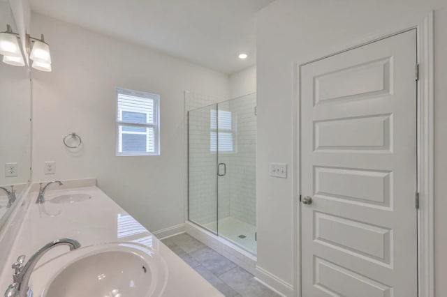 full bath featuring double vanity, a stall shower, a sink, and baseboards