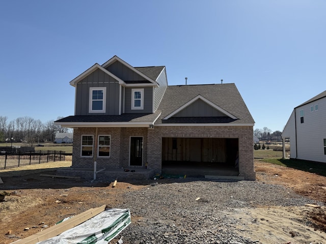 view of front of home featuring a garage, brick siding, board and batten siding, and fence