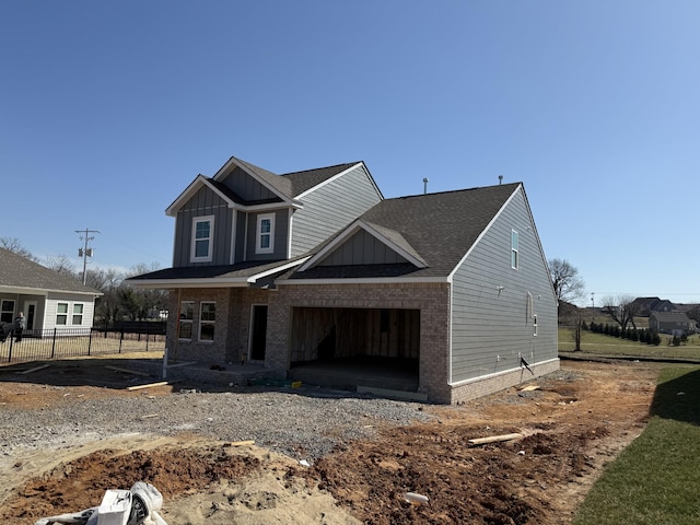 view of front of home featuring brick siding, board and batten siding, an attached garage, and fence