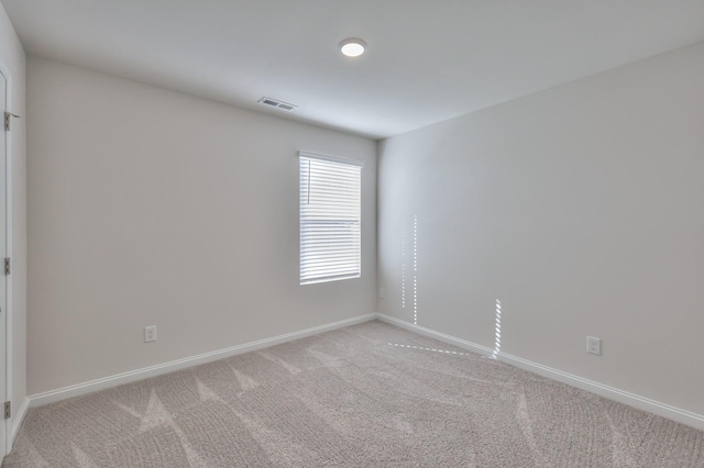 empty room featuring light colored carpet, visible vents, and baseboards