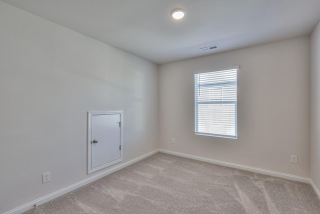 empty room with light colored carpet, visible vents, and baseboards