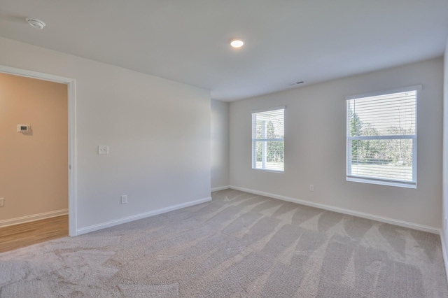 unfurnished room featuring light carpet, visible vents, and baseboards