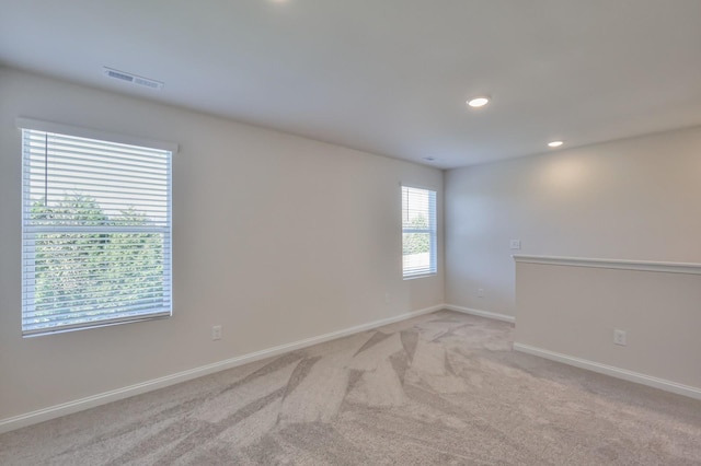 empty room with light colored carpet, visible vents, baseboards, and recessed lighting