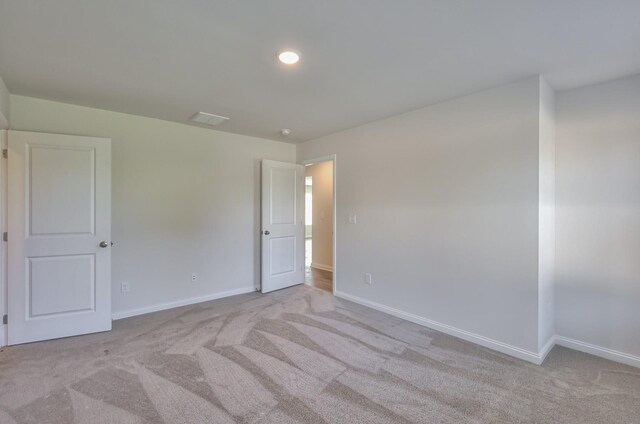 empty room with visible vents, baseboards, and light colored carpet