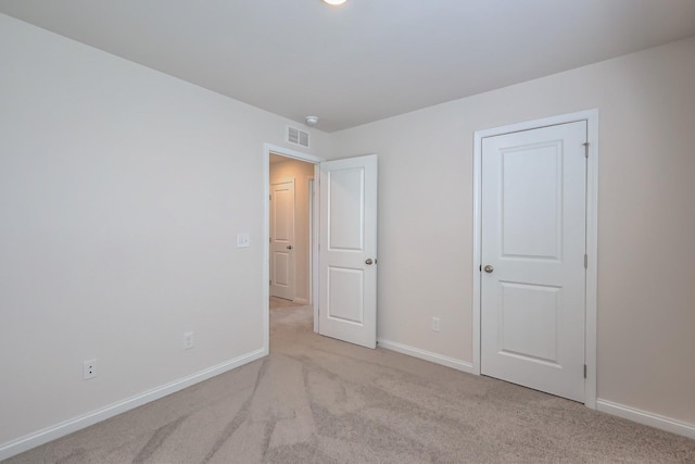 unfurnished bedroom featuring visible vents, light carpet, and baseboards