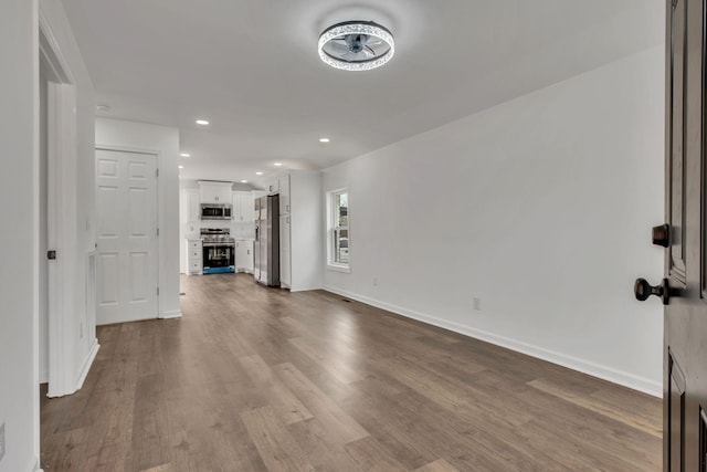 unfurnished living room with recessed lighting, dark wood finished floors, and baseboards