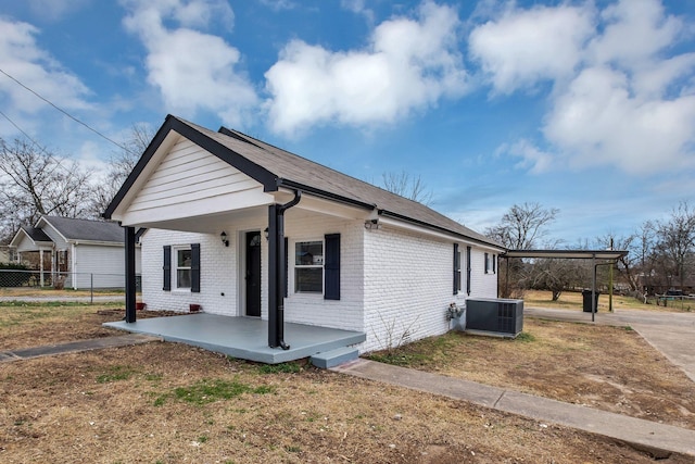 view of home's exterior with central air condition unit, fence, a porch, and brick siding