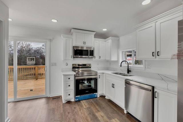 kitchen featuring stainless steel appliances, a sink, dark wood finished floors, and white cabinetry