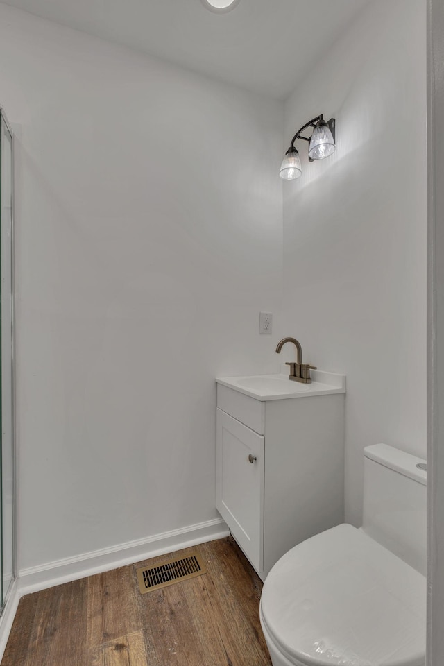 bathroom featuring baseboards, visible vents, toilet, wood finished floors, and vanity