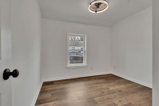 unfurnished room with wood finished floors, visible vents, and baseboards