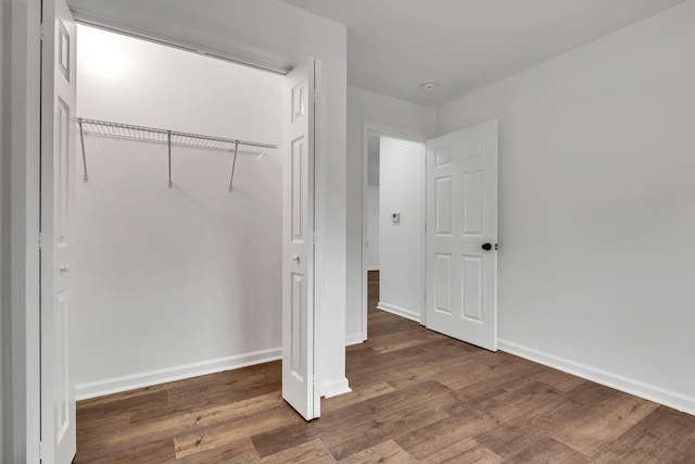 unfurnished bedroom with a closet, baseboards, and wood finished floors