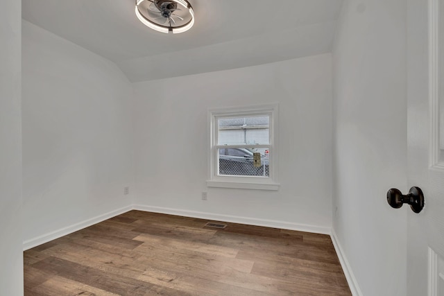 unfurnished room with lofted ceiling, dark wood-style flooring, visible vents, and baseboards