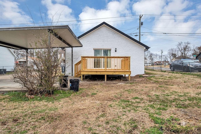 back of house featuring fence, a deck, central air condition unit, a carport, and brick siding