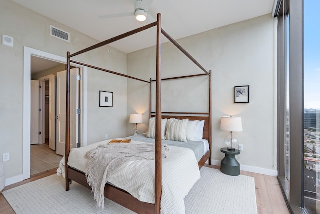 bedroom featuring a ceiling fan, wood finished floors, visible vents, and baseboards