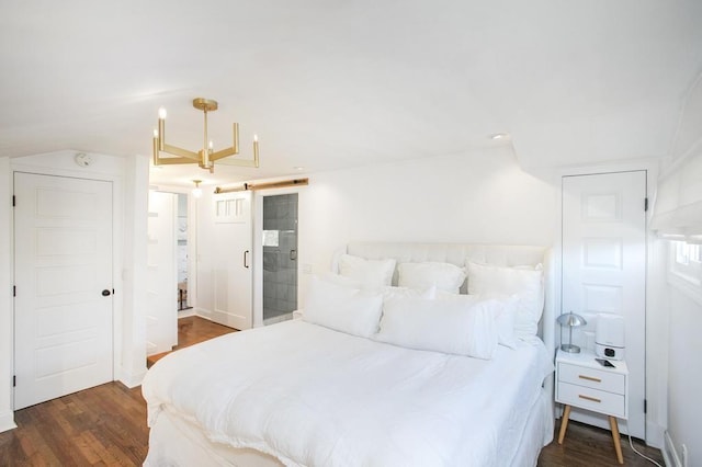 bedroom featuring vaulted ceiling, a barn door, and wood finished floors