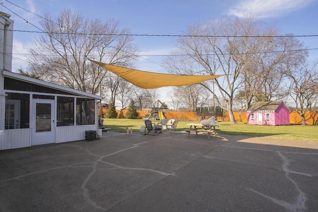 view of patio / terrace featuring a sunroom, a shed, and an outbuilding