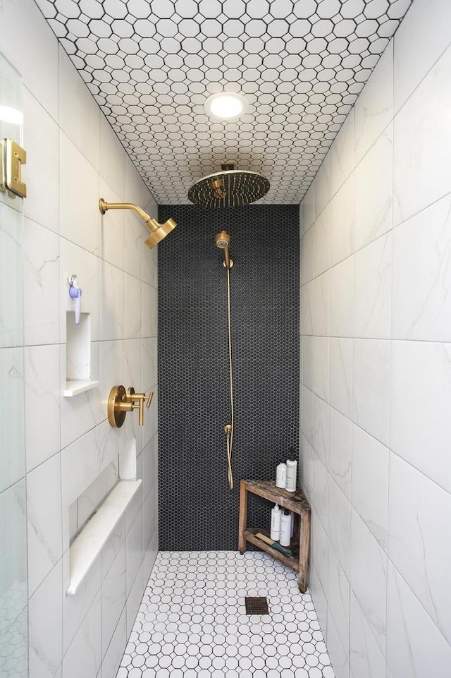 full bathroom featuring a tile shower and tile walls