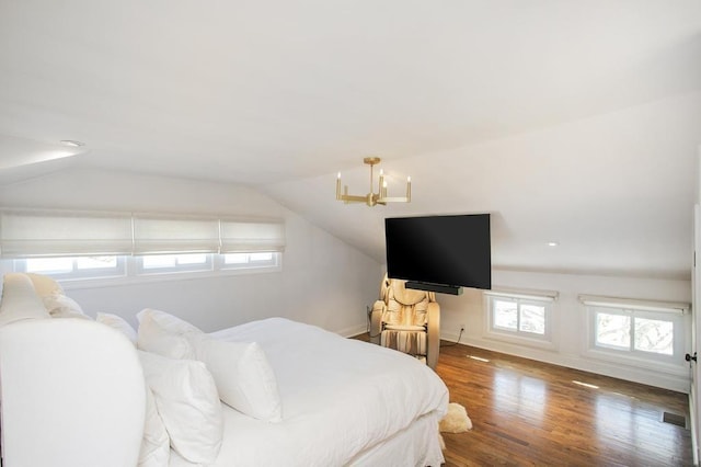 bedroom with lofted ceiling, wood finished floors, visible vents, and a notable chandelier