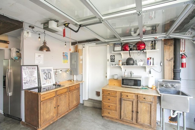 kitchen featuring stainless steel appliances, finished concrete flooring, light countertops, electric panel, and brown cabinets