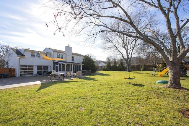 view of yard with a patio area, a playground, fence, and a sunroom