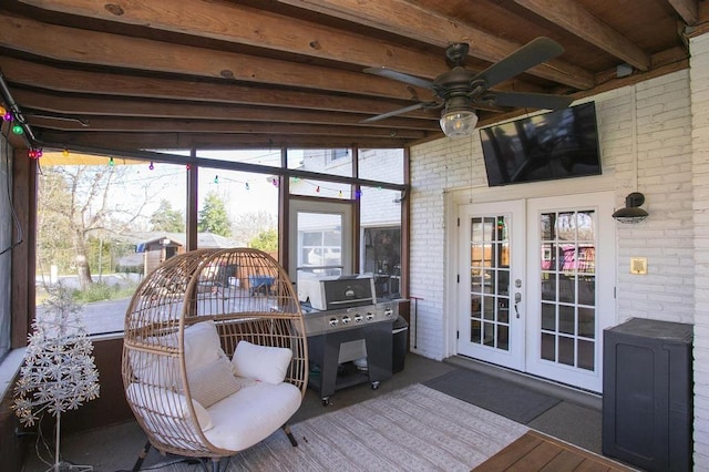 sunroom featuring a ceiling fan, beamed ceiling, and french doors