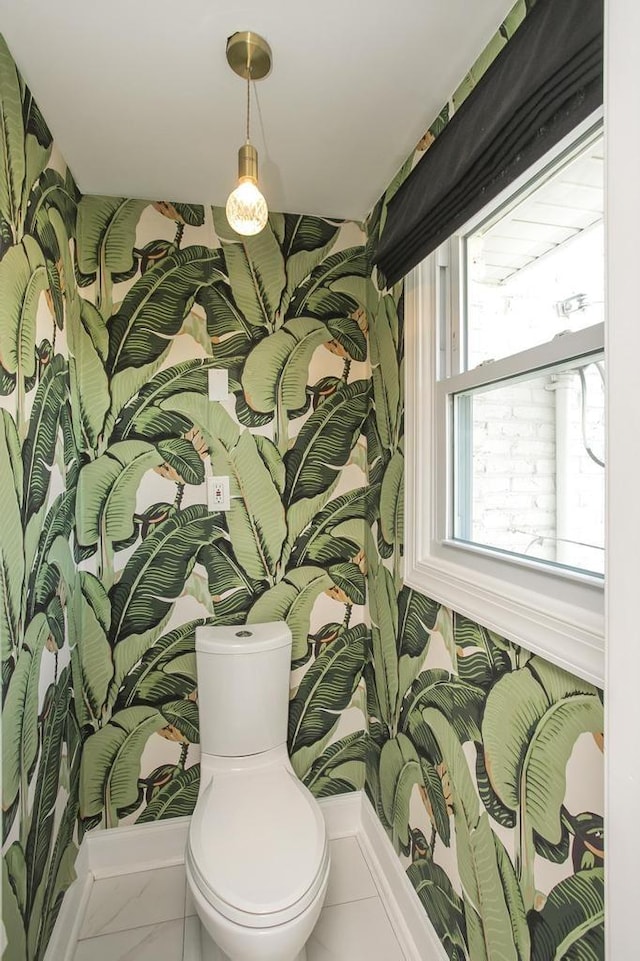 bathroom with marble finish floor, toilet, and wallpapered walls