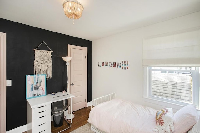 bedroom featuring an inviting chandelier, wood finished floors, and baseboards