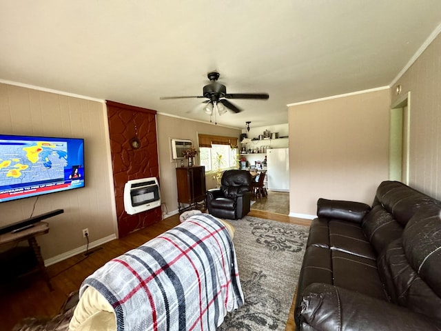 living area featuring a ceiling fan, crown molding, heating unit, and wood finished floors