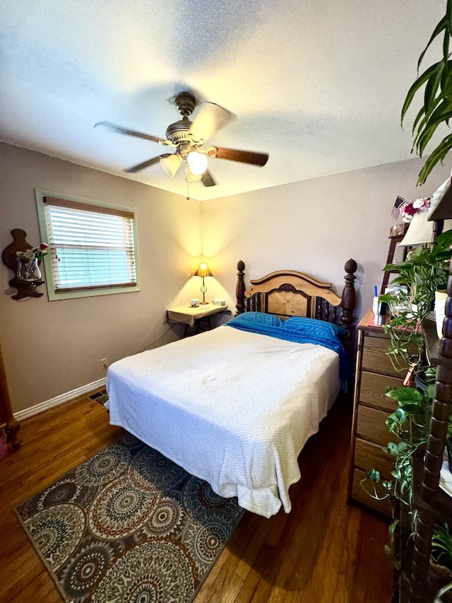 bedroom featuring ceiling fan, a textured ceiling, wood finished floors, and baseboards