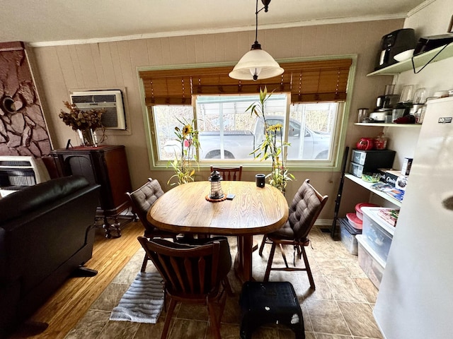 dining space with an AC wall unit, crown molding, and wood finished floors