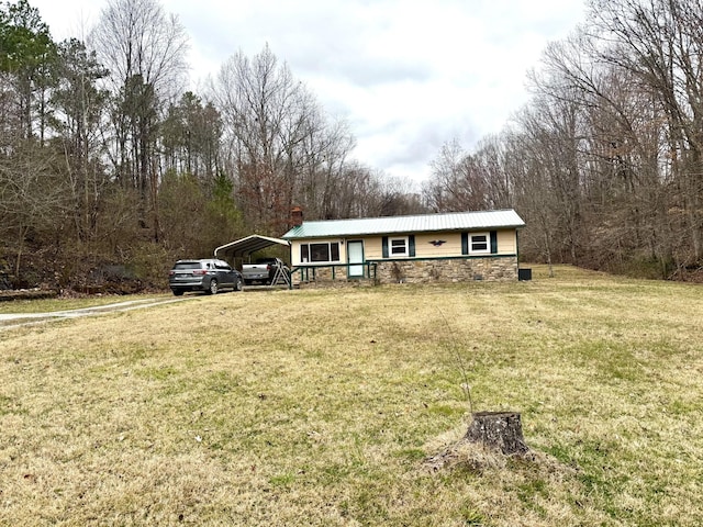 view of front facade with metal roof, stone siding, a carport, and a front yard