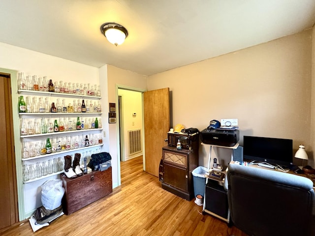 office with visible vents, a bar, and light wood finished floors