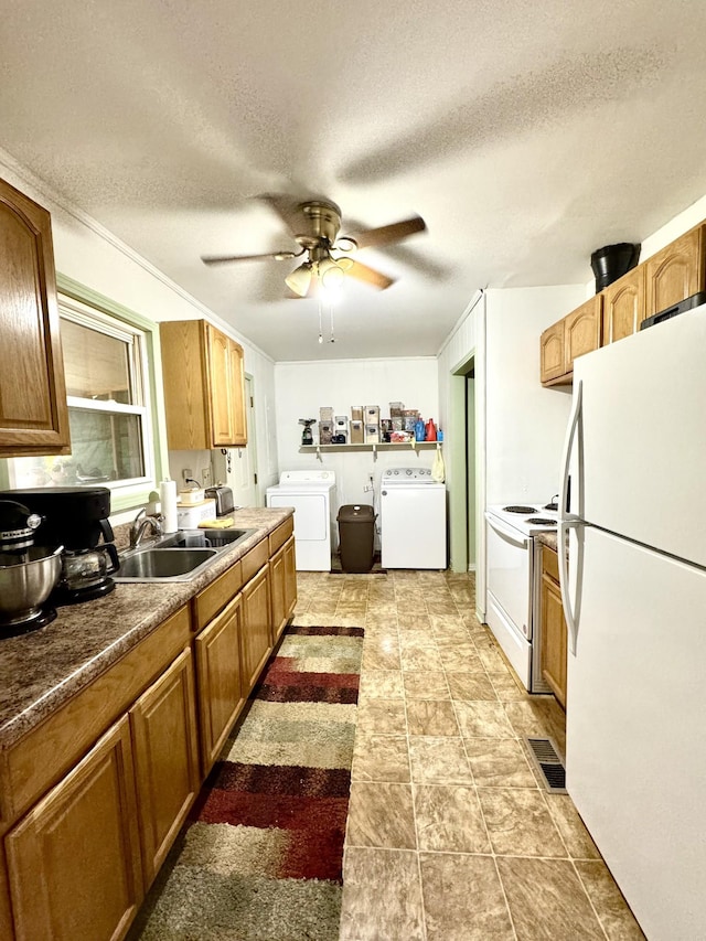 kitchen featuring visible vents, ceiling fan, a sink, separate washer and dryer, and white appliances